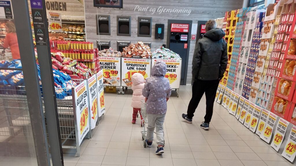 dentro del supermercado, un hombre caminando con dos ninas