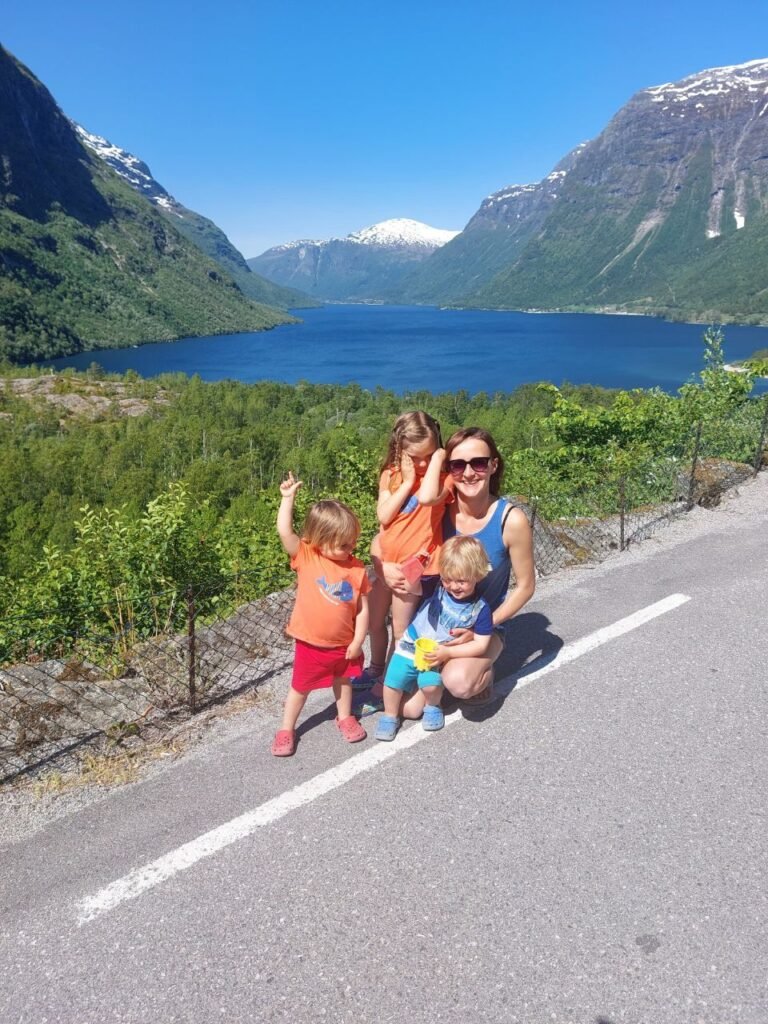 mujer y tres ninos enfrente de fiordo en Noruega