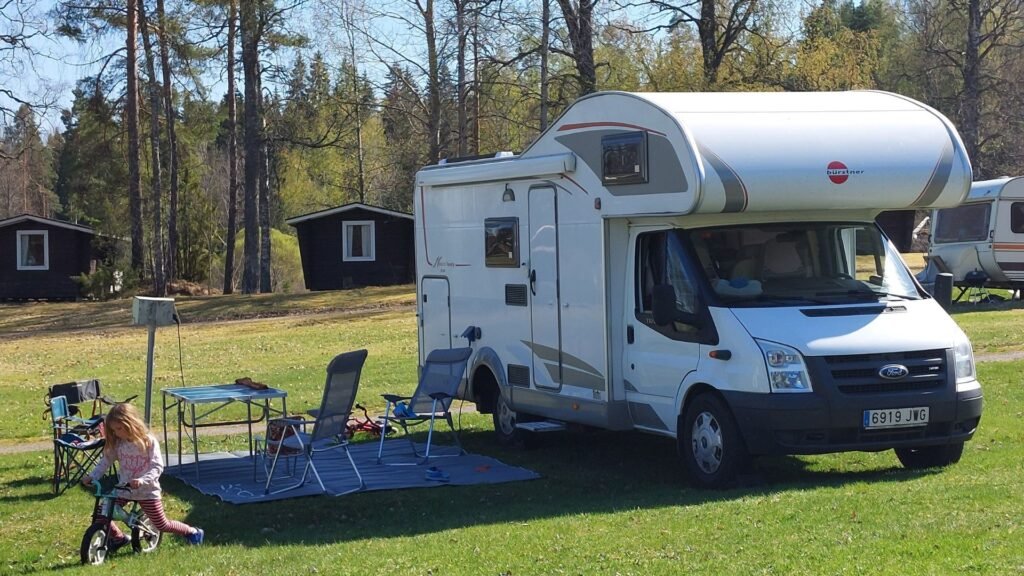 autocaravana aparcada en un camping en Finlandia, la nina en la bicicleta