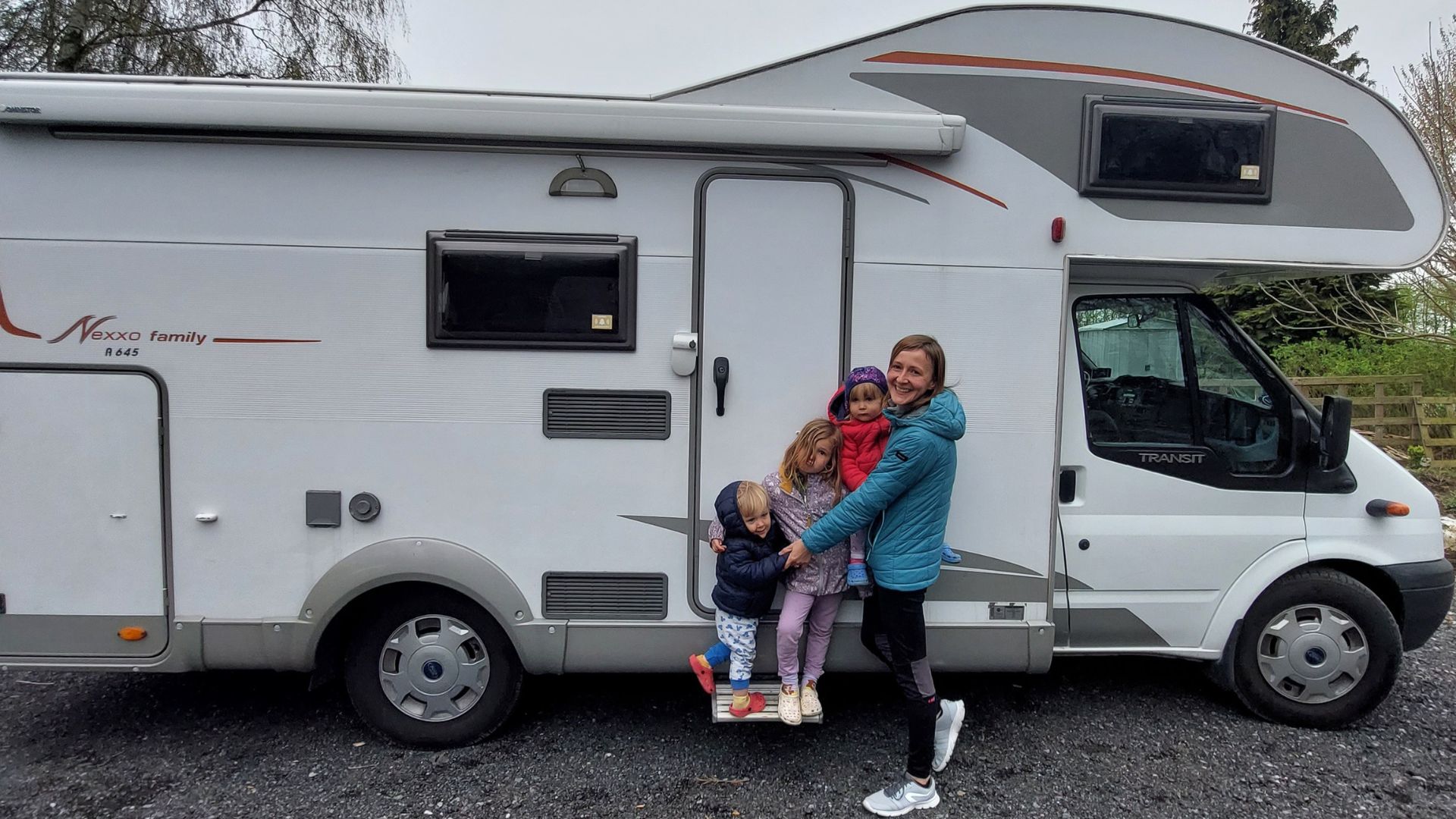 autocaravana capuchina con la familia (mujer y tres niños) enfrente.