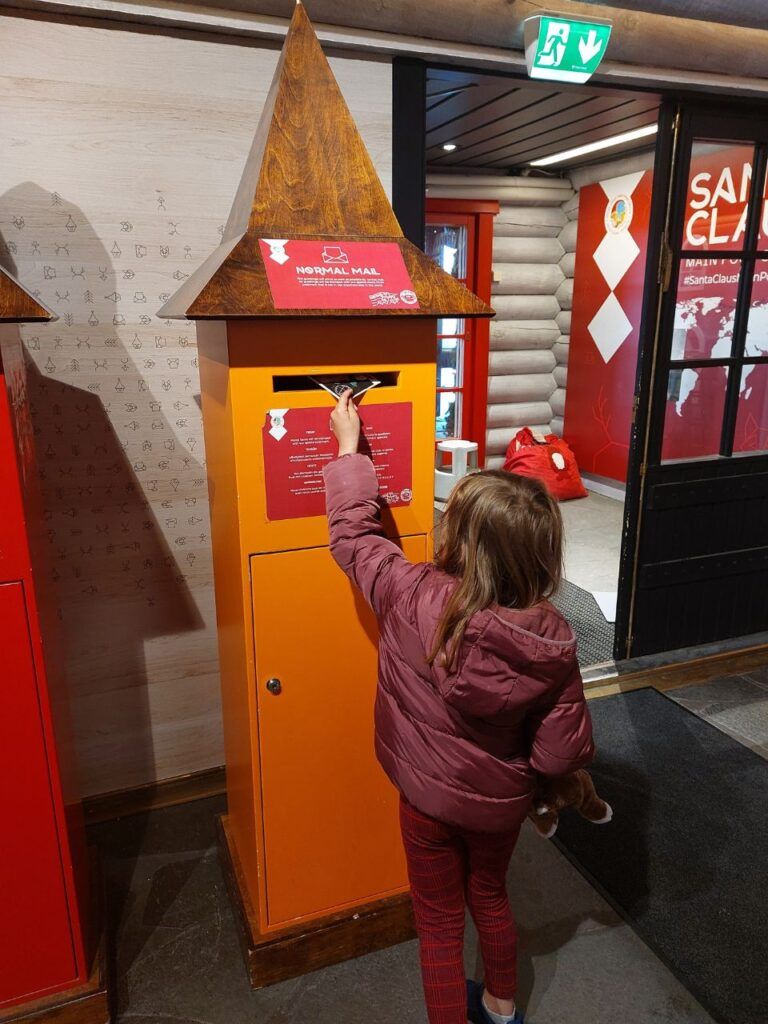 Nina poniendo la carta en el buzon en Oficina de Correos de Papa Noel en Rovaniemi, Finlandia