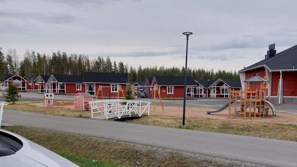 vista al pueblo de Papa Noel en Rovaniemi, Finlandia. Se ve un poquito autocaravana, parque infantil, el puente blanco y casas rojas.