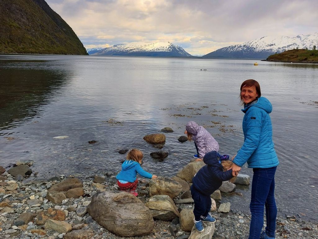 madre con tres ninos pequenos en frente de fiordo en Noruega