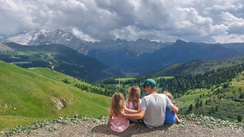 Un padre con tres hijos mirando a las montanas, Passo Sella, Dolomitas, Italia