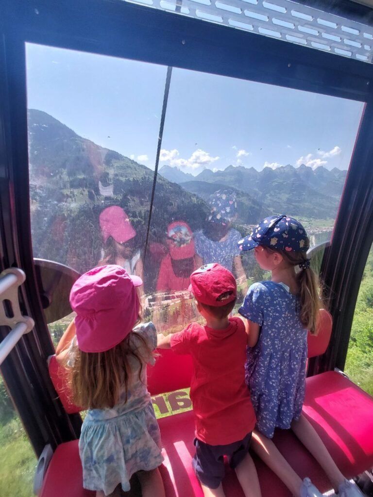 tres ninos subiendo en telecabina Predazzo Gardone en Dolomitas, Italia