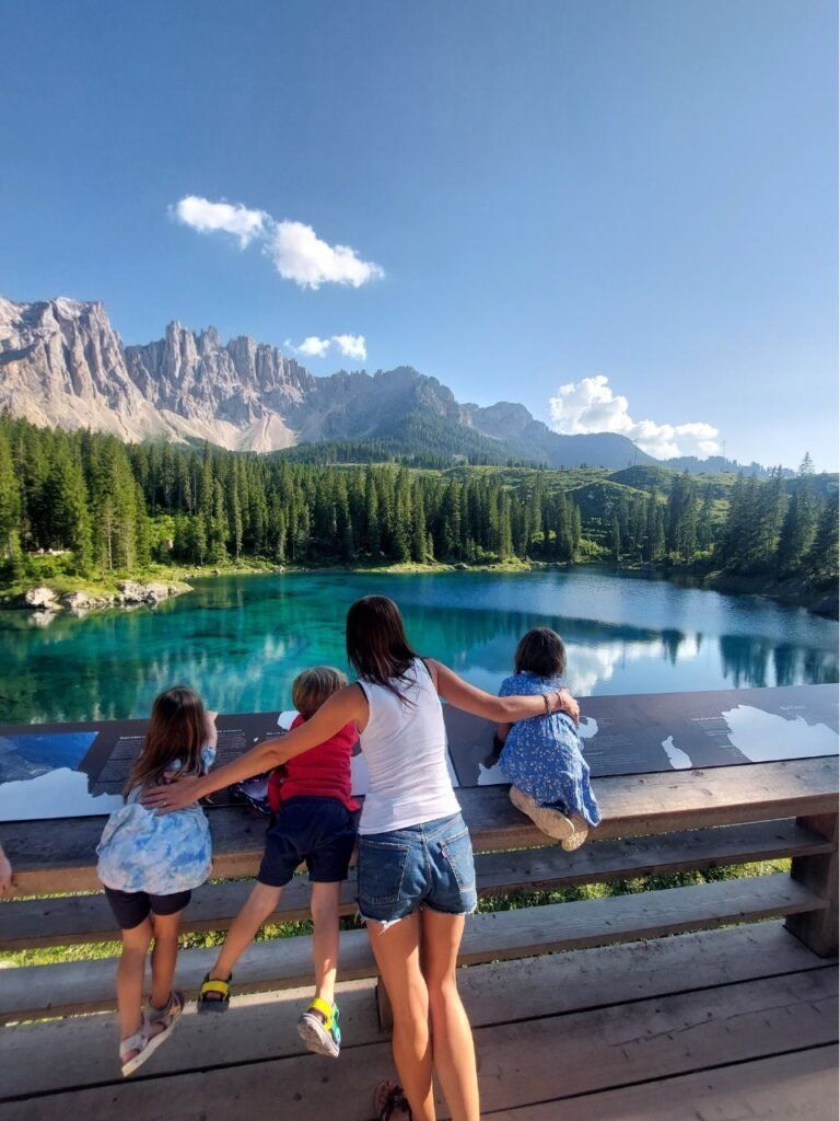 mujer y tres ninos mirando al Lago di Carezza en Dolomitas
