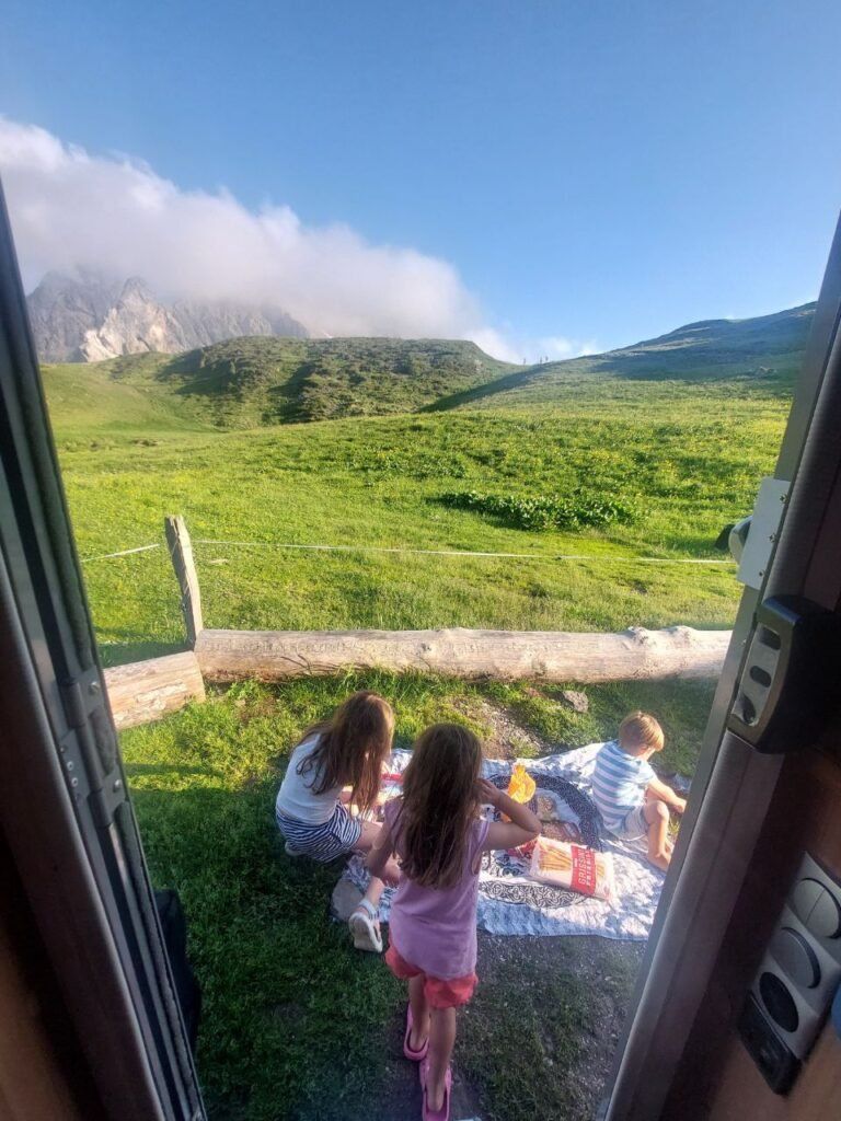 ninos jugando delante de autocaravana en Passo Giau, Italia