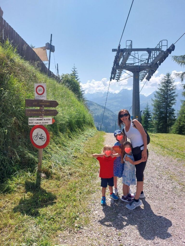 mujer con tres ninos en dolomitas, italia al lado de telecabina Predazzo Gardone