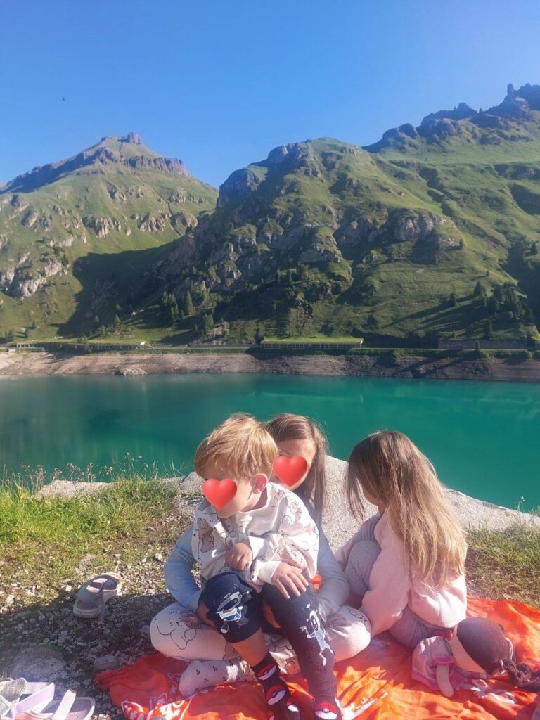 Tres ninos jugando enfrente de Lago di Fedaia, dolomitas, Italia