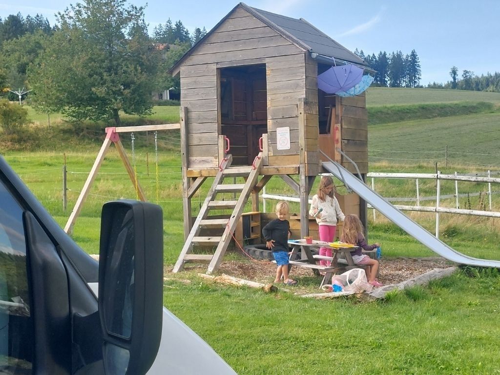 niños jugando en el parque infantil al lado de autocaravana